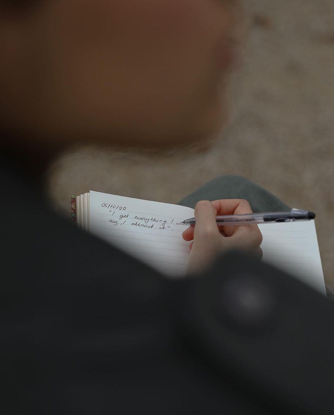 Person schreibt in einem Notizbuch mit einem Stift, fokussiert auf das Schreiben. Hypnowriting hilft, Gedanken zu ordnen und emotionale Blockaden zu lösen.