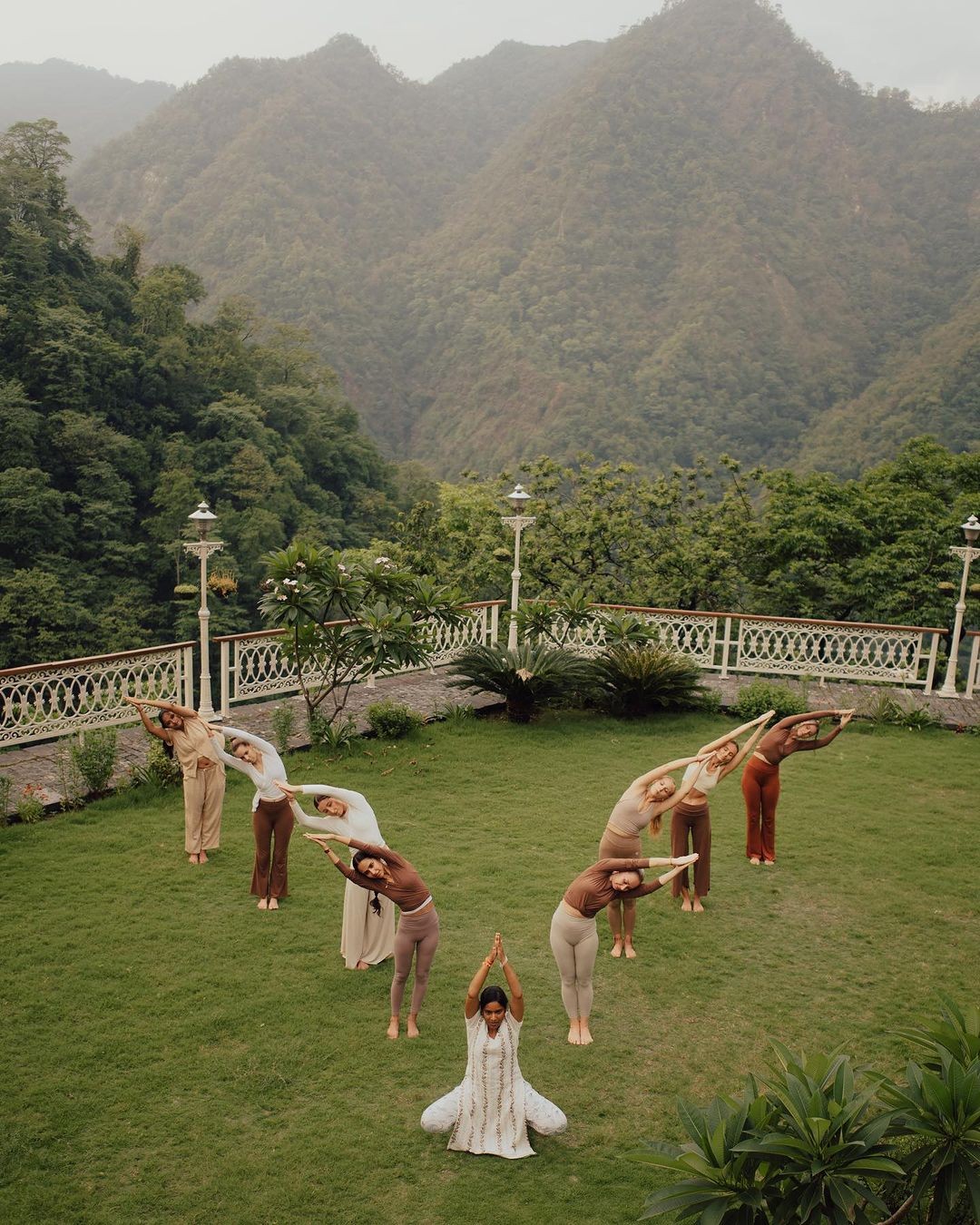 Eine Gruppe praktiziert Yoga im Freien, bildet mit ihren Körpern das Wort 'Mantra' – symbolisiert die transformative Kraft von Mantren für ein besseres Leben.