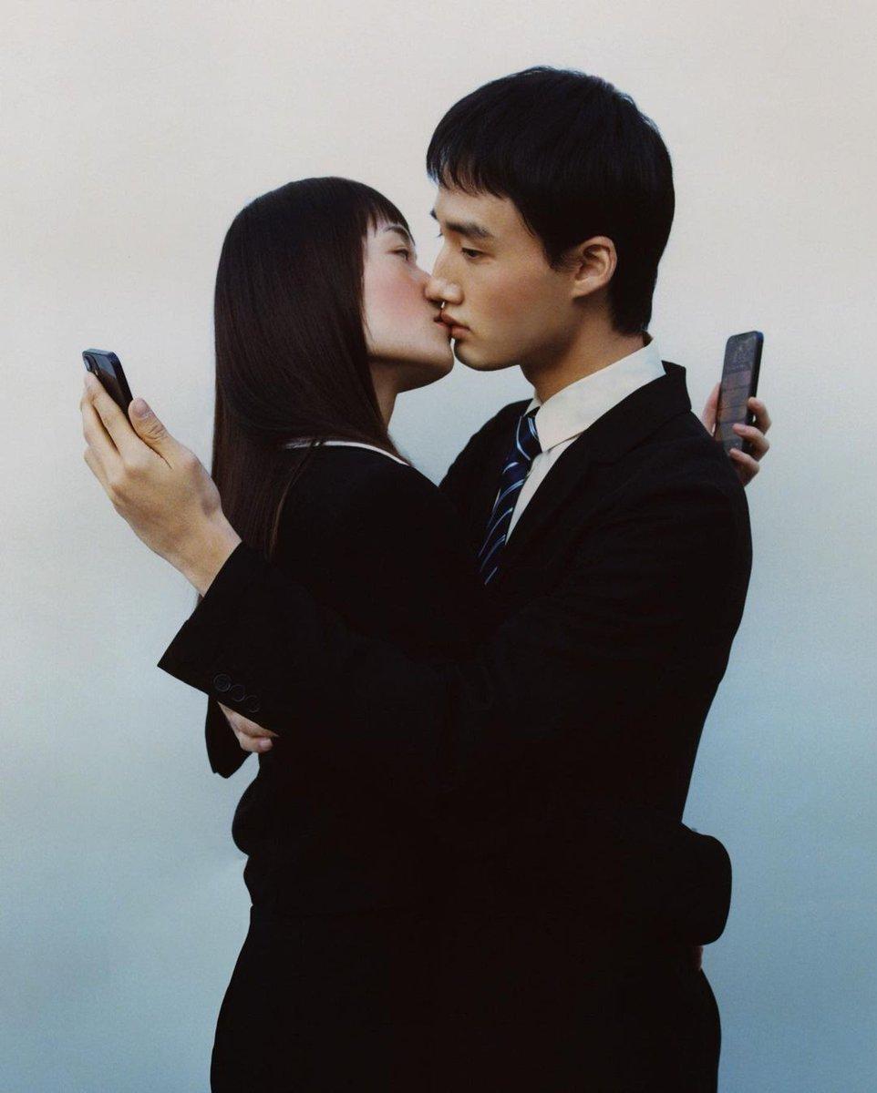 Ein Paar, das sich küsst, während beide auf ihre Smartphones schauen, symbolisiert die emotionale Entfremdung und Einsamkeit, die durch Dating-Apps verstärkt wird.