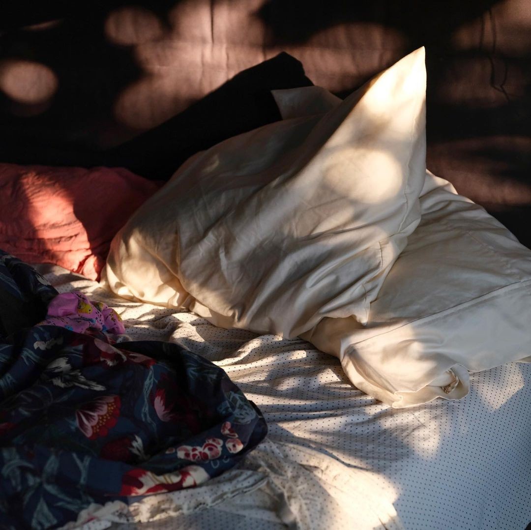 Gemütliches Bett im sanften Morgenlicht – symbolisiert das langsame Aufwachen, begleitet von einem motivierenden Guten-Morgen-Spruch.