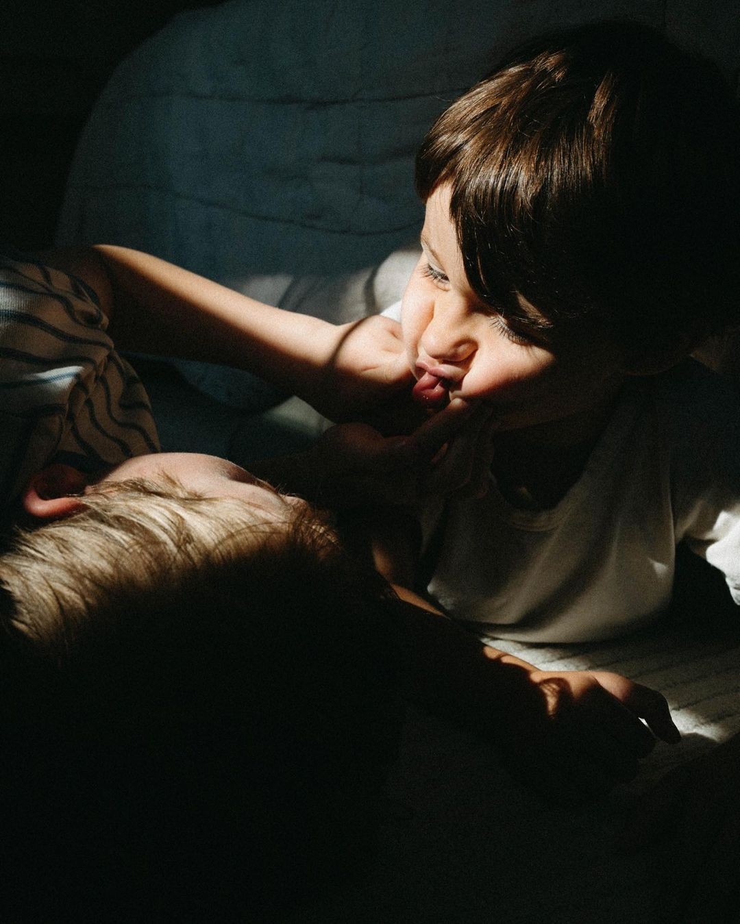 Zwei Kinder spielen liebevoll miteinander im Halbschatten, was soziale Interaktion und emotionale Bindungen fördert – wichtige Faktoren für ein starkes Immunsystem bei Kindern.