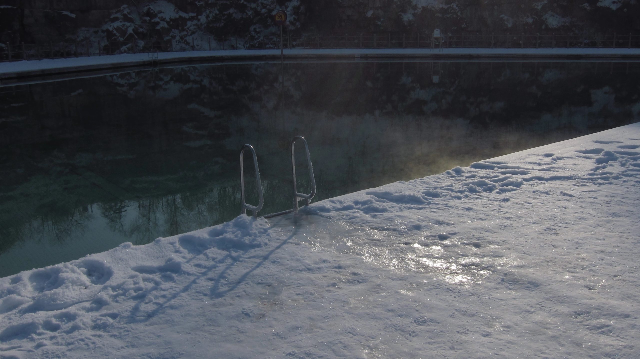 Verschneiter Einstieg in einen gefrorenen See – Eisbaden erfordert Vorbereitung und mentale Stärke, um die kalten Bedingungen zu meistern.