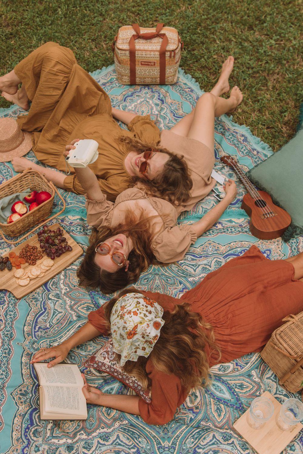 Freundinnen genießen ein entspanntes Picknick im Grünen. Stressabbau durch gemeinsames Lachen und entspannte Zeit mit Freunden.