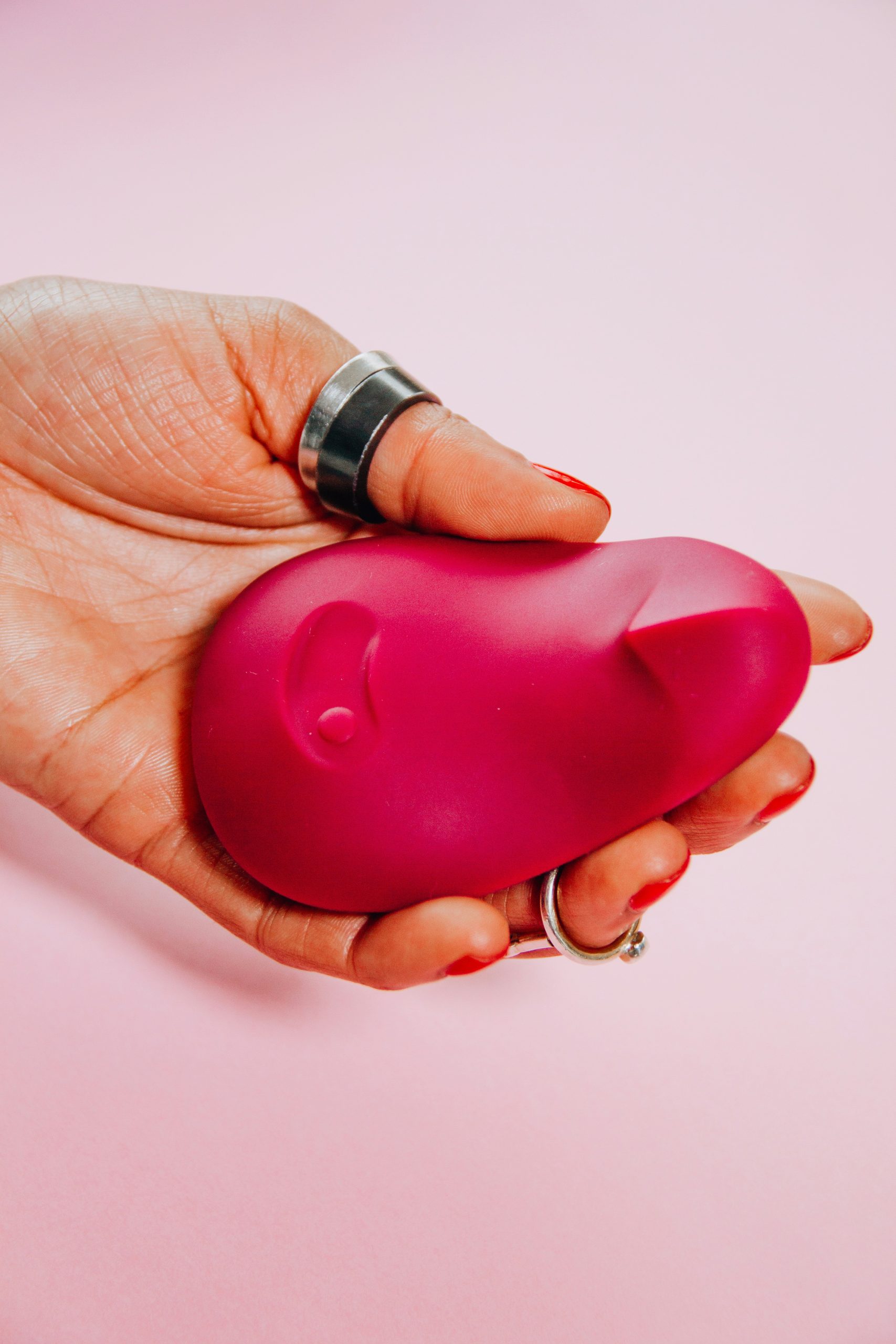 Hand hält einen pinken Vibrator, stilvoll in einem intimen und modernen Setting präsentiert