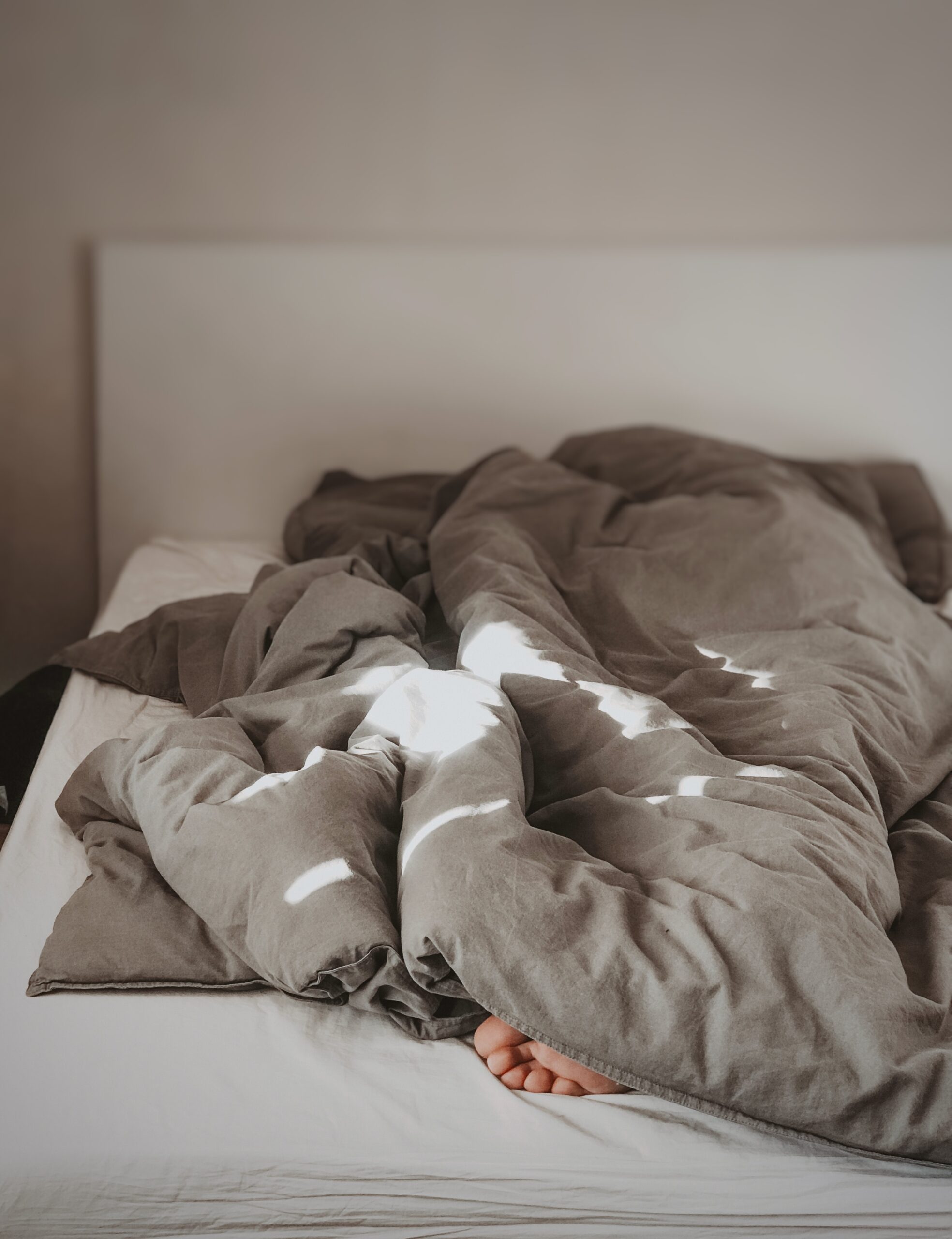 Keine Guten-Morgen-Sprüche in Sicht: Mensch versteckt sich unter Bettdecke.