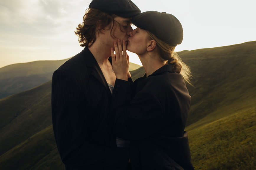 Ein junges Paar küsst sich liebevoll auf einem Hügel